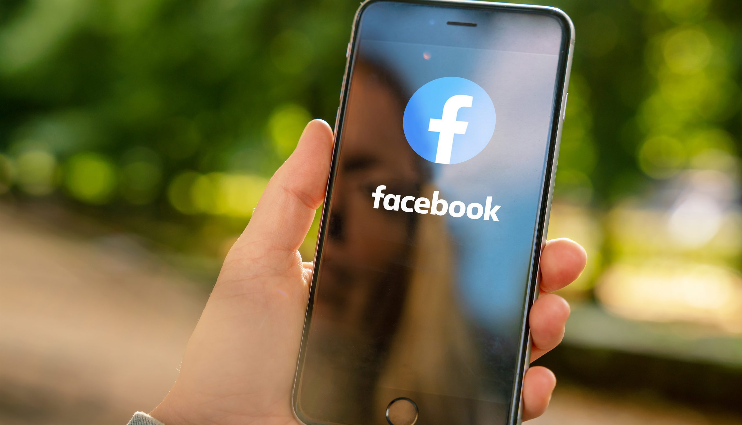 AACHEN, GERMANY AUGUST 2019: Woman holding a Apple iPhone opening Facebook app in a car. Facebook is the world largest social media plattform